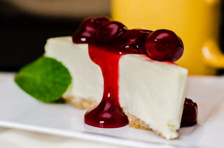 Slice of cherry cheesecake and coffee with mint garnish.   Shallow depth of field.  の写真素材