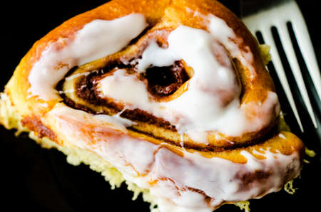 Cinnamon bun with fork on black background.の写真素材