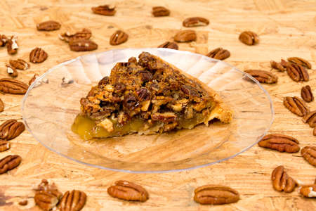 Pecan pie slice with pecans on wooden backgroundの写真素材