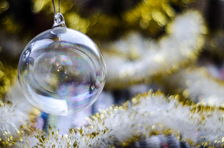 Transparent glass Christmas toy with yellow garlands closeup