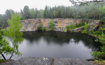 Abandoned flooded quarry in the forest. Lake in the forest. Geological outcrops.