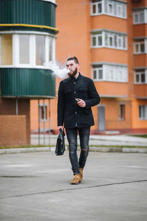 Guy with  beard smoking electronic cigarette outdoor