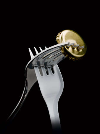 Steel and plastic fork pierces a beer-cover.の写真素材
