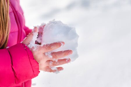 A little girl holds a snowball in the hands. Soft focus.