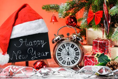 A blackboard with the text Happy New Year written in a chalk covered with a Santa Claus hat on a...