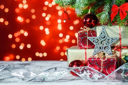 Silver star and gifts on a wooden board covered with snow under a Christmas tree on shiny background with copy space for text.の写真素材