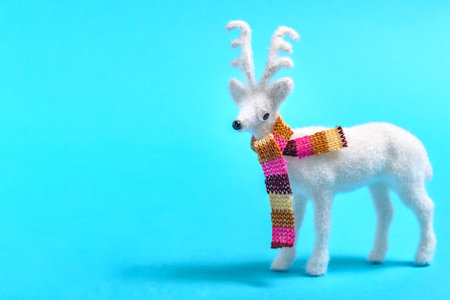 White reindeer with a colorful scarf on a pastel blue background. Christmas or New Year minimal concept.の写真素材