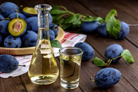 Plum brandy or schnapps in glasses and fresh tasty plums on a wooden tableの写真素材