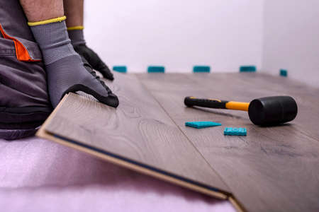 Male hands is laying wooden panel of laminate floor in the room. Selective focus.の写真素材