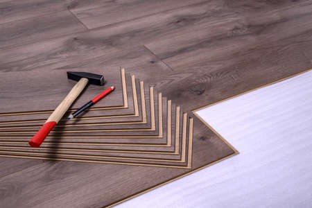 Hammer and pencil on laminate panels, carpenter tools for laying laminate in the room.