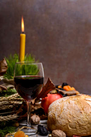 Traditional food for orthodox Christmas eve. Yule log or badnjak, wine, bread, apple, cereals, dried fruits and burning candle on rustic table. Concept celebration orthodox Christmas.の写真素材