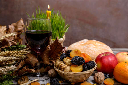 Traditional food for orthodox Christmas eve. Yule log or badnjak, wine, bread, apples, cereals, dried fruits and burning candle on rustic table. Concept celebration orthodox Christmas.の写真素材