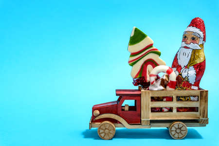 Christmas holiday celebration concept. Wooden toy truck with Christmas sweets on blue background.