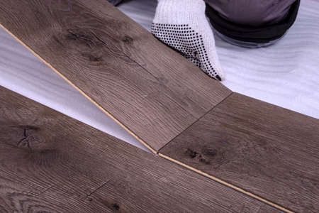 Male hands is laying wooden panel of laminate floor in the room. Selective focus.の写真素材