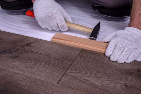 Male hands is laying wooden panel of laminate floor in the room. Selective focus.の写真素材