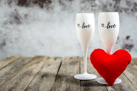 Valentine's Day concept. Two glasses for wine and red plush heart  on a wooden table. Selective focus.の写真素材