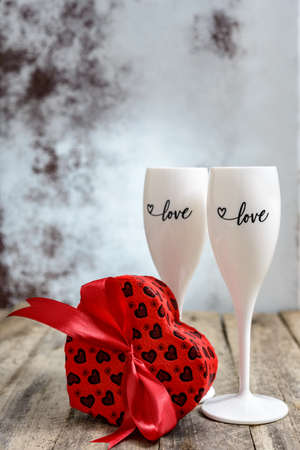 Valentine's Day concept. Two glasses for champagne and heart shaped gift box on a wooden table. Selective focus.の写真素材