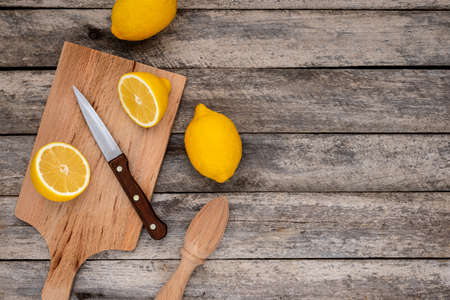 Fresh lemon cut in half with knife on wooden cutting board. Top view.の写真素材