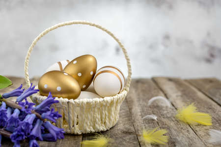 Basket of colorful Easter eggs and a bouquet of hyacinths on a rustic wooden table. Easter concept.の写真素材