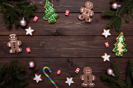 Christmas composition with gingerbread cookies, fir tree branches and christmas decor on wooden table with copy space for text.の写真素材