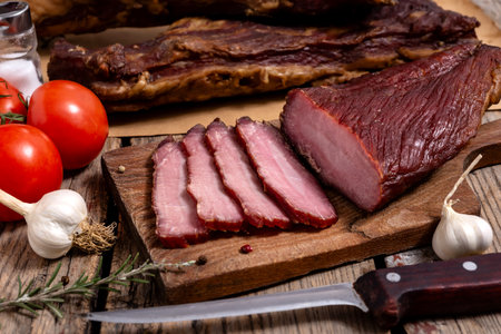 Cutting board with dried meat, vegetables, spice and kitchen knife on a wooden table. Selective focus.の写真素材