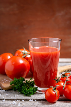 Glass of tasty tomato juice and fresh tomatoes on wooden table. Selective focus.の写真素材