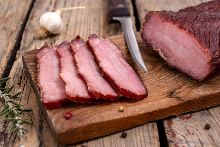 Cutting board with dried meat, spice and kitchen knife on a wooden table. Selective focus.の写真素材