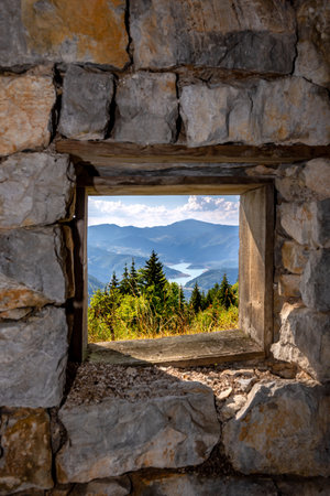 View of Lake Zaovine from an old window frame on a rough stone wall on Tara mountain in Serbia.の写真素材