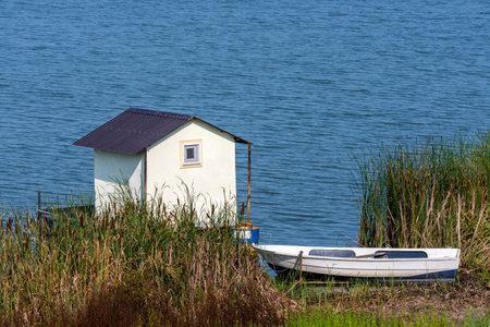A small fishing house on a raft with a boat next to the shore on a lake.の写真素材