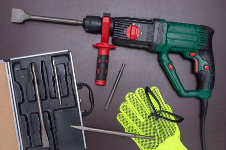 Hammer drill with a set of accessories and protective gloves and safety glasses on a working table.の写真素材