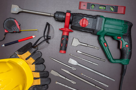 Hammer drill with a set of accessories and protective equipment on a working table.の写真素材