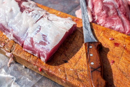 Cutting board with raw pork meat and kitchen knife on a wooden table. Selective focus.の写真素材
