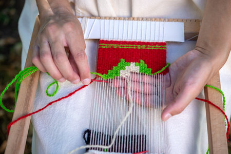 Close-up of a woman weaver's hand using a weaving needle on a hand loom. Selective focus.の写真素材