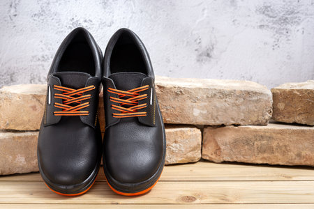 A pair of new work shoes leaning against old bricks lined up on a wooden table. Selective focus.の写真素材