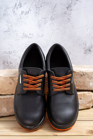 A pair of new work shoes leaning against old bricks lined up on a wooden table. Selective focus.の写真素材