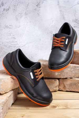 A pair of new work shoes leaning against old bricks lined up on a wooden table. Selective focus.の写真素材