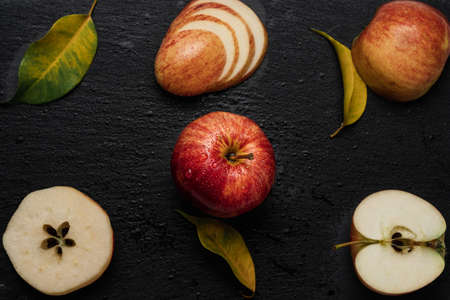 Red an yellow apples cut in different ways with leaves. Apples on a cutting boardの写真素材