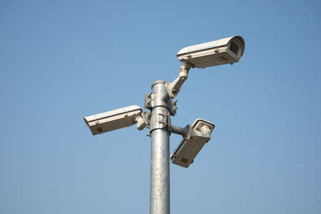 Three direction CCTV security camera on iron post blue sky background