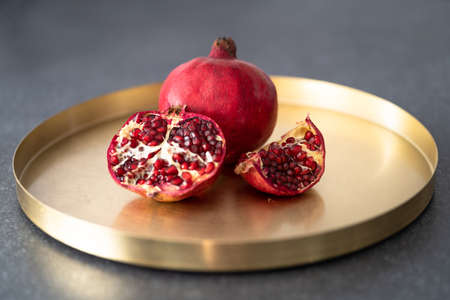 Pomegranate served on a golden tray. Pieces of lumber lie on a plate.の写真素材