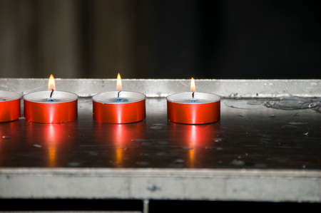 ROME, ITALY - AUGUST 6, 2012: Red burning candles photographed  in a church in Rome.のeditorial素材