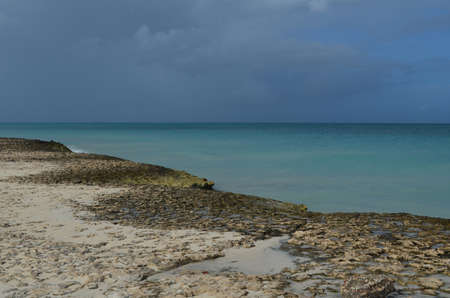 Aruba with sand washed lava rocks on the coastline.