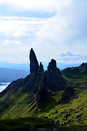 Jutting rocks of Old Man of Storr with lush green landscape and blue skies.の写真素材
