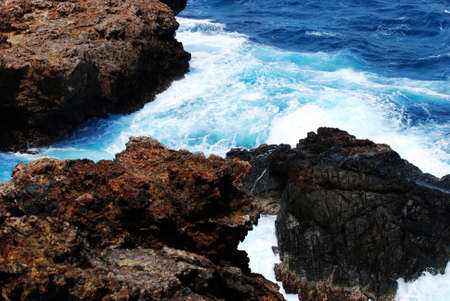 Rugged lava rock with water swriling around and crashing on the rocks.
