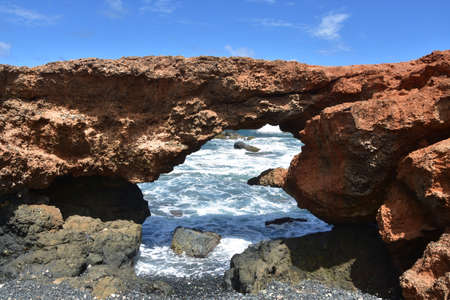 Scenic black stone beach natural lava rock bridge in Aruba.