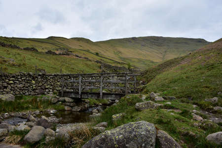 Wooden foot bridge through the fells of the lake district in England.の写真素材
