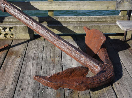 Rusty boat anchor on a dock in a harbor.の写真素材