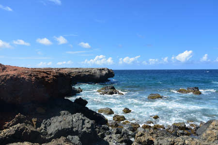 Waves crashing ashore on black lava rock coastline of Aruba.の写真素材