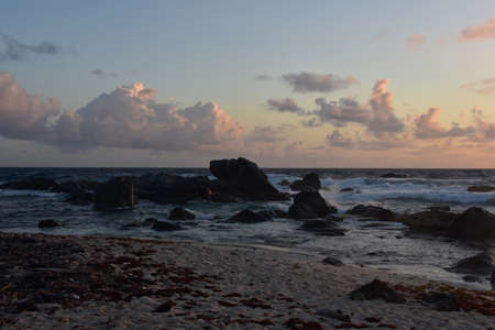 Gorgeous sunrise seascape with rugged rocks exposed in ocean.