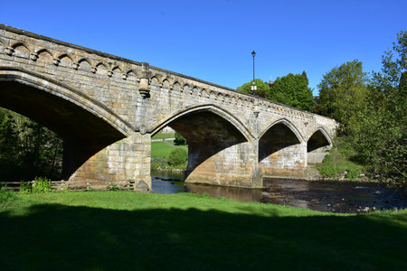 River with an old stone arched bridge in England.