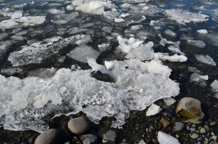 Beautiful view of melting icebergs in a lagoon and on a black sand beach.
